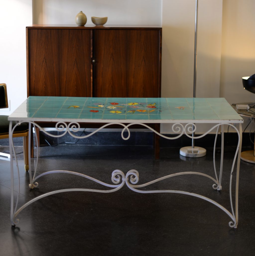 Mesa de hierro forjado y tapa de azulejos con decoración pintada a mano.