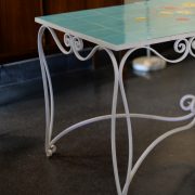 Mesa de hierro forjado y tapa de azulejos con decoración pintada a mano. Detalle